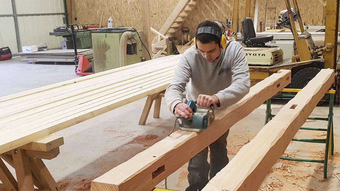 Artisan travaillant sur la rénovation d'une charpente en bois